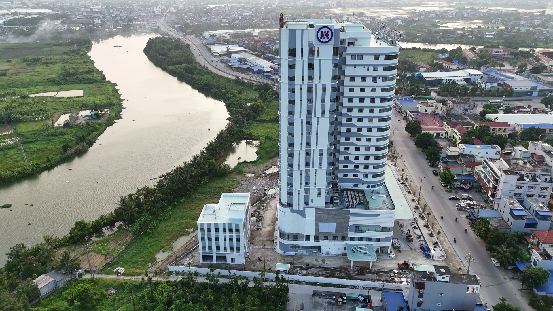 Bệnh viện Đa khoa Quốc tế Thủy Nguyên đứng bên dòng sông Trịnh uốn cong, xung quanh là khu dân cư và ruộng