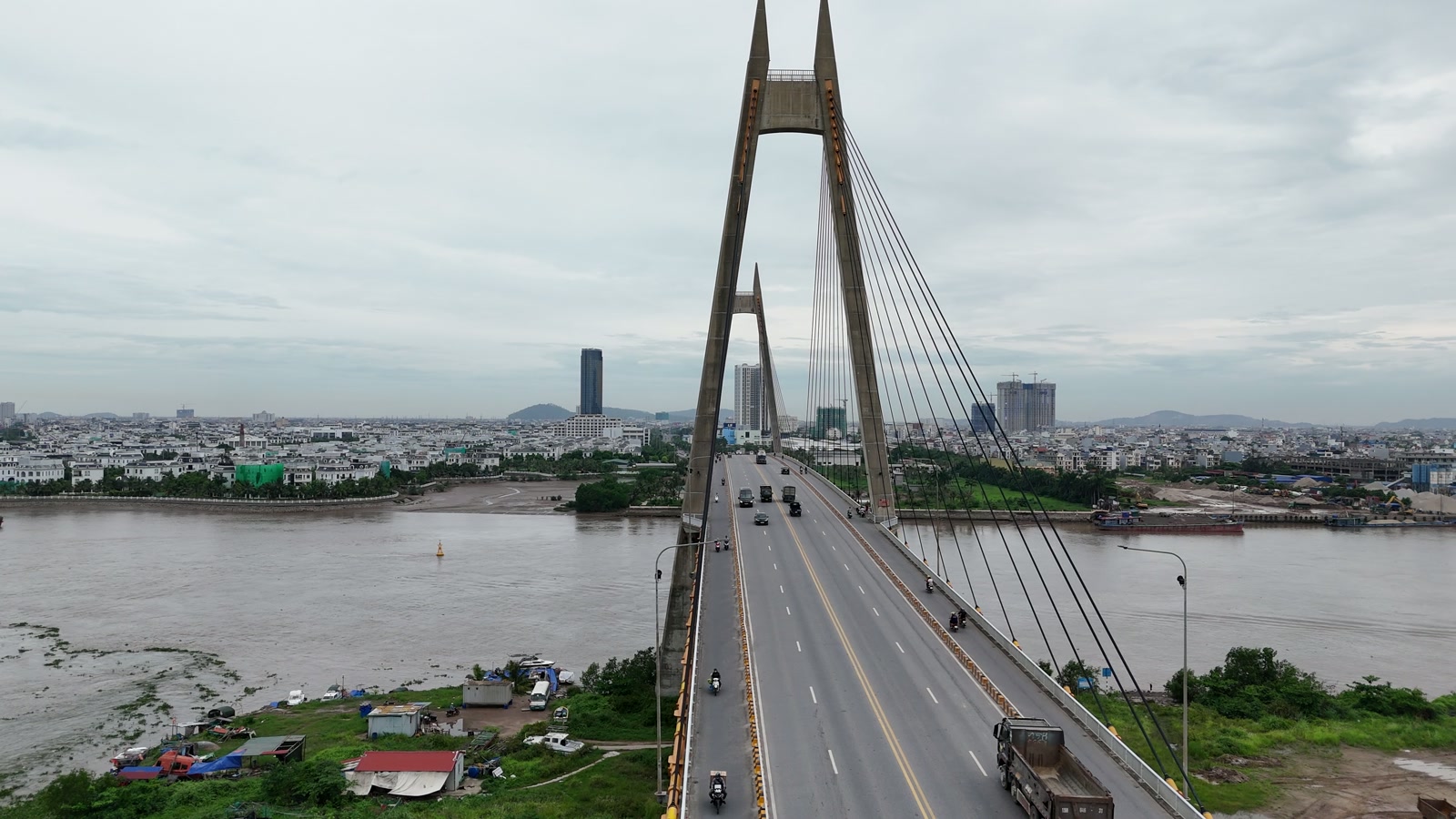 Cầu Bính dây văng hai tháp bắc qua sông Cấm sang Bắc Sông Cấm, trên mặt cầu có ô tô và xe máy chạy, phía xa bên kia là nội đô Hải Phòng