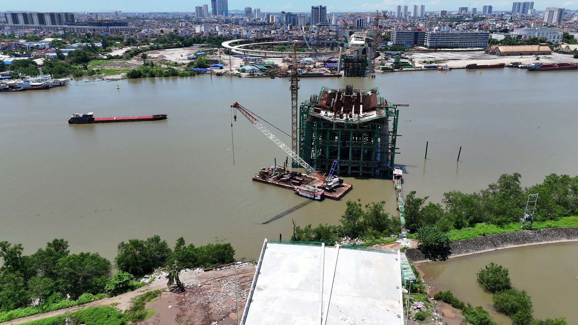 Trụ tháp cầu Nguyễn Trãi đang thi công giữa sông Cấm tháng 7/2026, xung quanh có cần cẩu, xà lan và giàn giáo