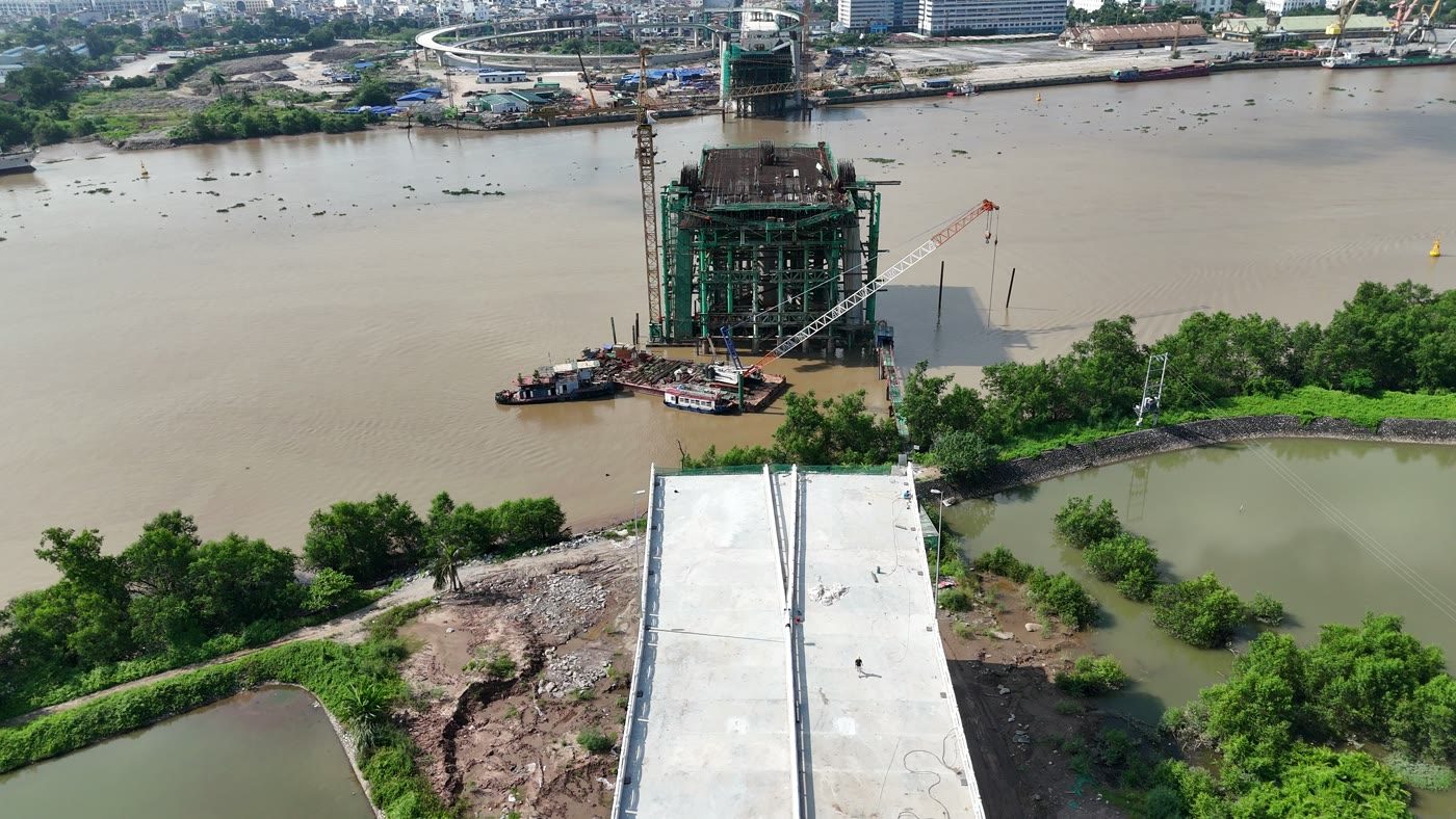 Trụ tháp cầu Nguyễn Trãi đang xây giữa sông Cấm, thân tháp còn thấp và bọc giàn giáo, khoảng giữa hai trụ vẫn là mặt nước chưa có nhịp cầu