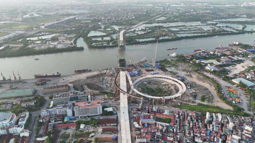 Cầu Nguyễn Trãi đang xây vượt sông Cấm sang Bắc Sông Cấm, phía dưới là khu phố nội đô Hải Phòng san sát, phía trên bên kia sông là vùng đầm và đất còn trống