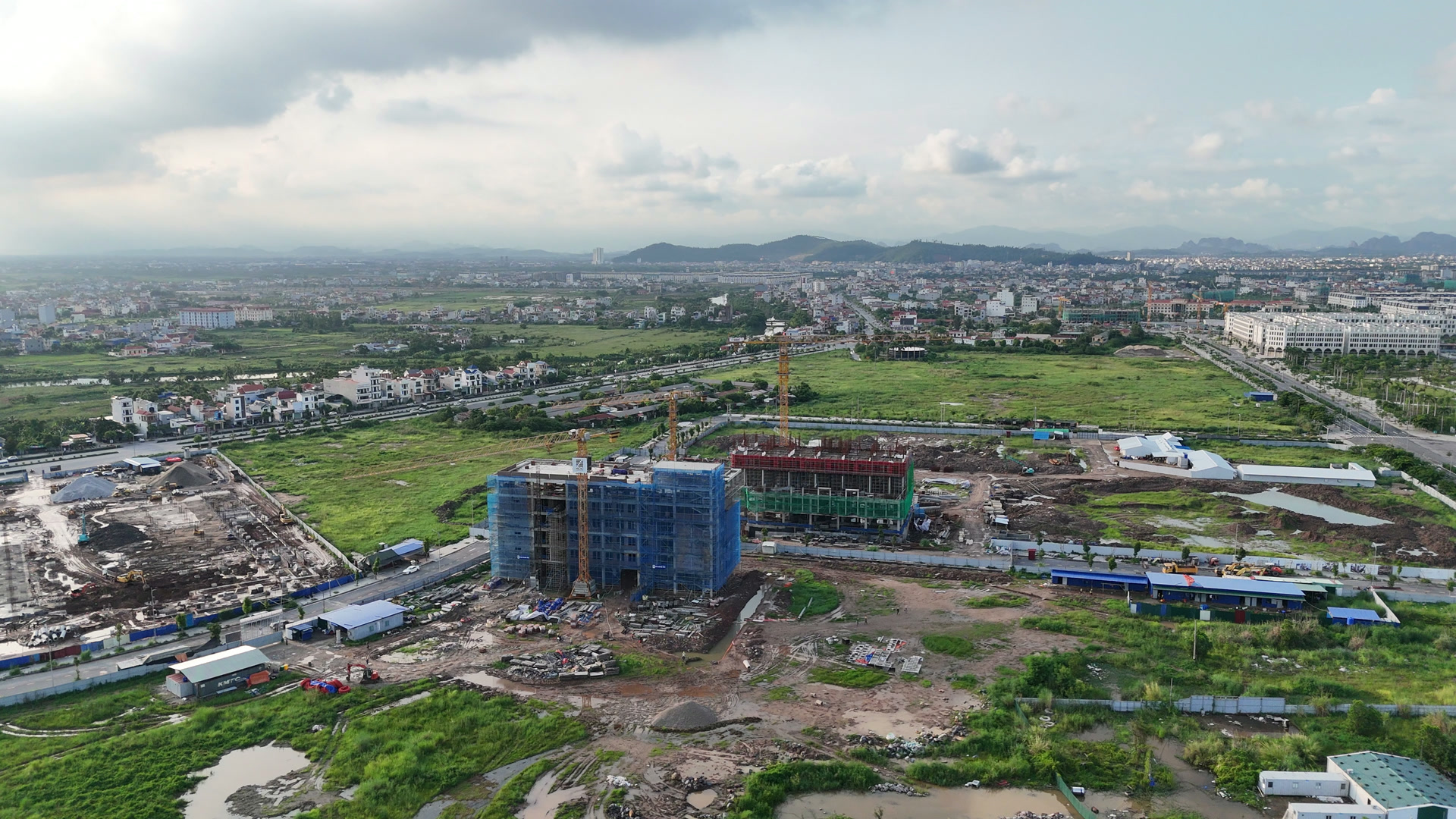 Tổ hợp giáo dục EQuest quây lưới xanh da trời đứng cạnh công trường Central Point, nhìn từ phía trung tâm hành chính mới Hải Phòng