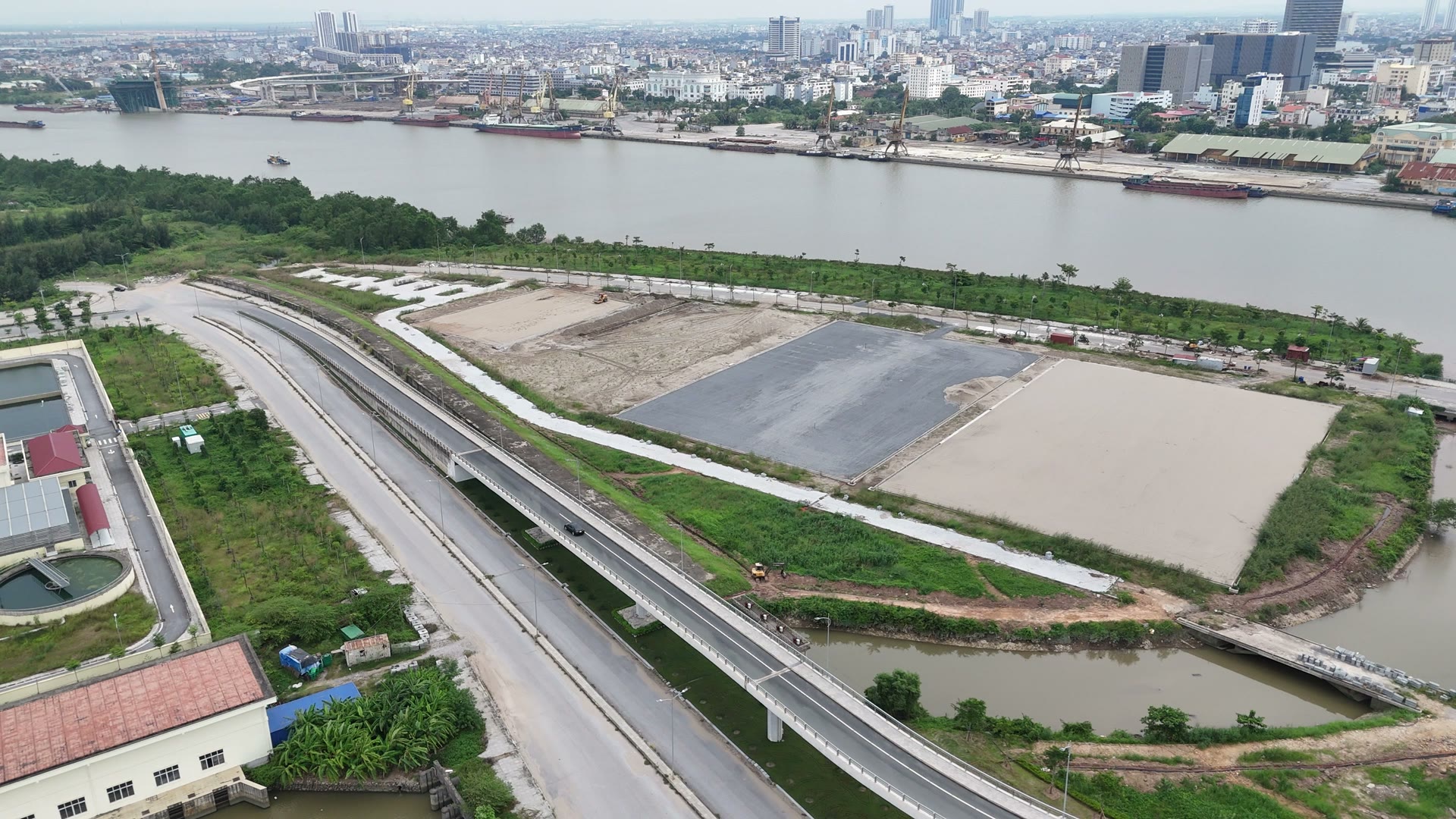 Hai ô đất lớn vuông vức đã san phẳng sát chân cầu Hoàng Văn Thụ, một ô phủ lớp nền sẫm màu, bên cạnh là đường ven sông Cấm và một con kênh nhỏ