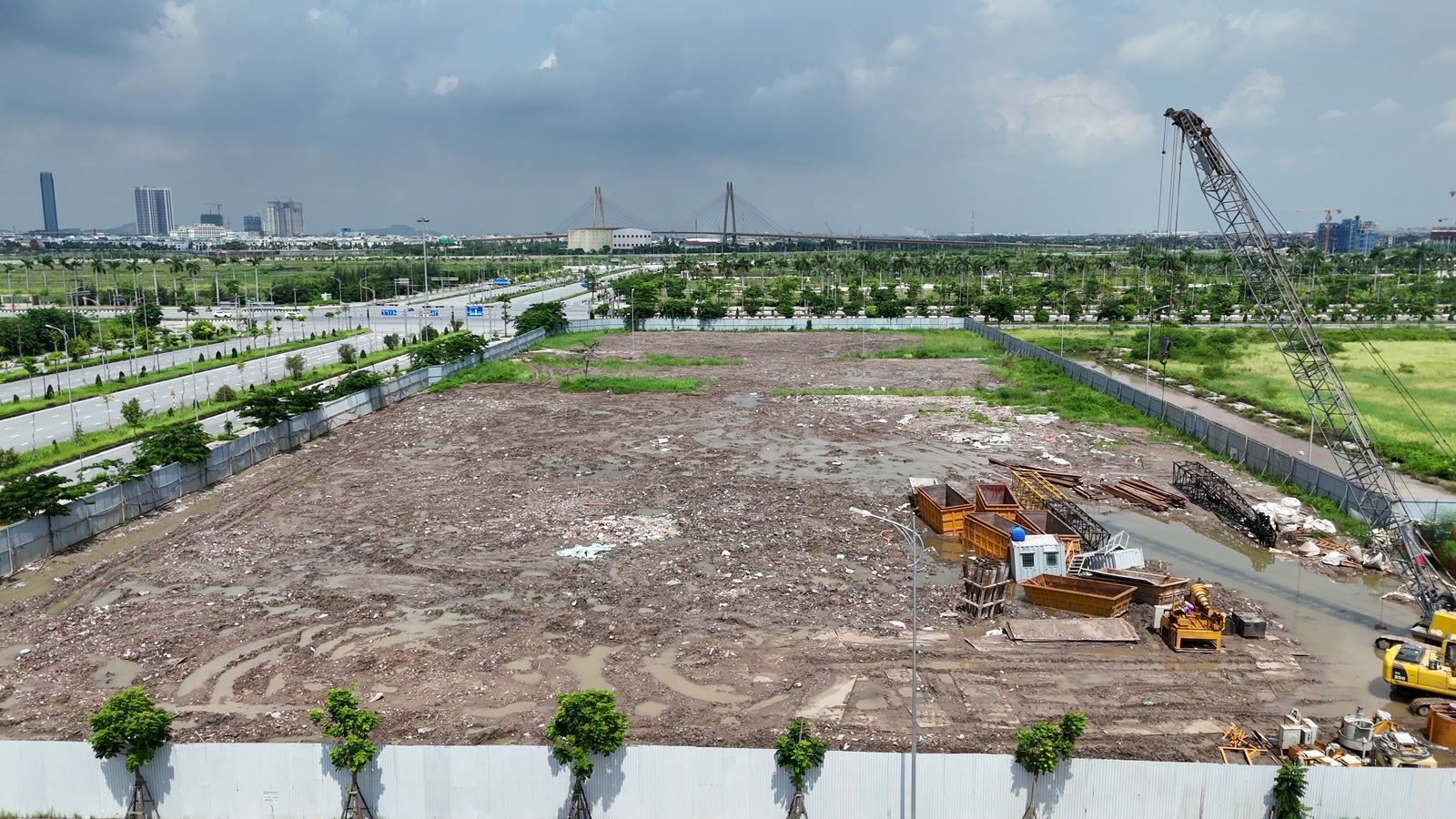 Công trường DOJI tại ngã tư đường Đông Tây với trục Đỗ Mười, mặt bằng đã dọn, máy móc làm phần dưới mặt đất, phía xa là cầu Hoàng Văn Thụ