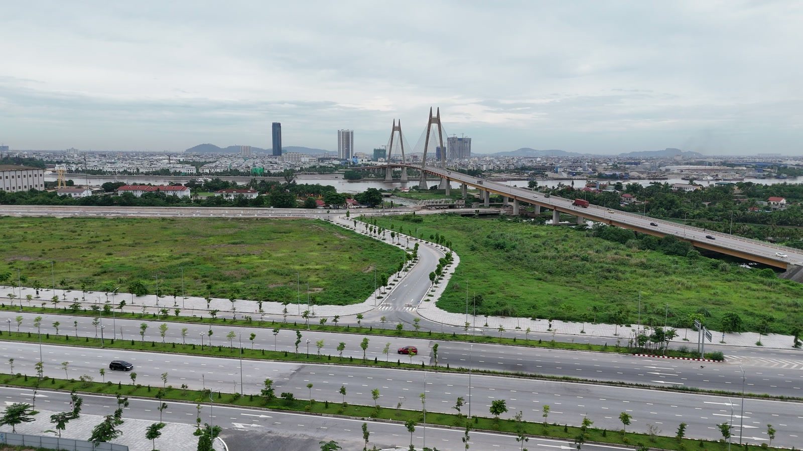 Đường Đông Tây uốn vòng chạy về phía chân cầu Bính, tháp dây văng của cầu hiện rõ phía xa bên kia sông Cấm