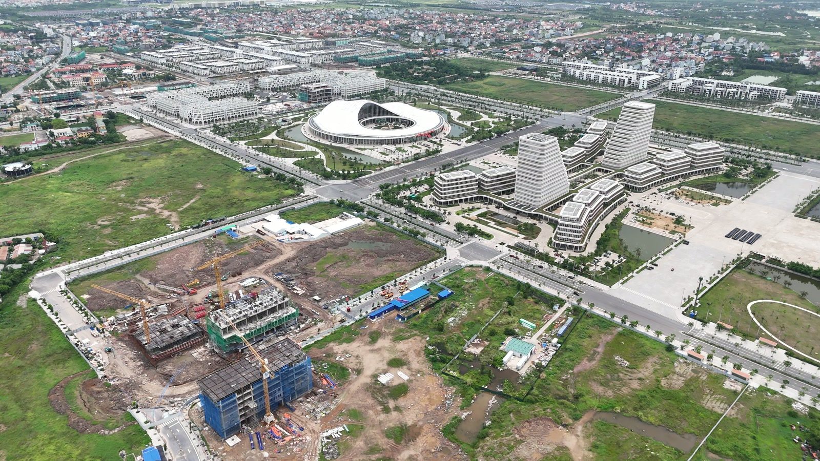 Đường Đông Tây chạy qua trước khu trung tâm chính trị hành chính Bắc Sông Cấm, toà nhà dáng con tàu hai cánh buồm và trung tâm hội nghị nhìn từ trên cao