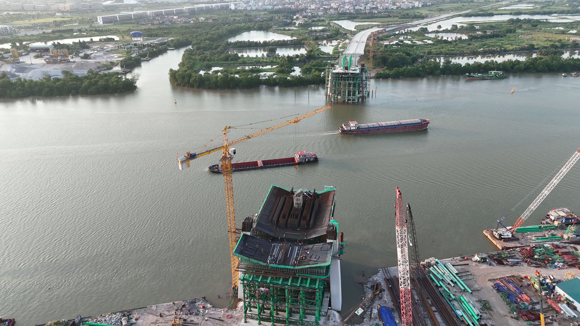 Khoảng giữa sông Cấm của cầu Nguyễn Trãi còn trống, hai sà lan chở hàng đang chạy qua đúng khoảng nước giữa hai trụ tháp đang thi công