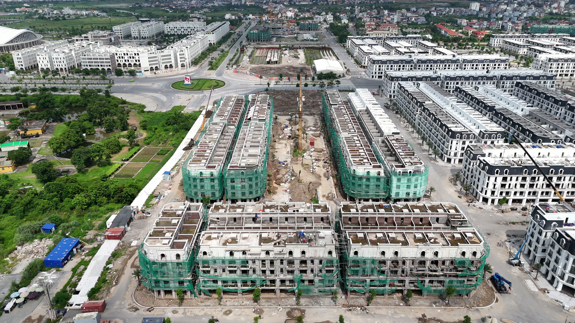 Những dãy nhà thấp tầng ở Hoàng Huy New City còn phủ lưới xanh và giàn giáo, bên cạnh là các dãy đã sơn trắng xong mặt ngoài