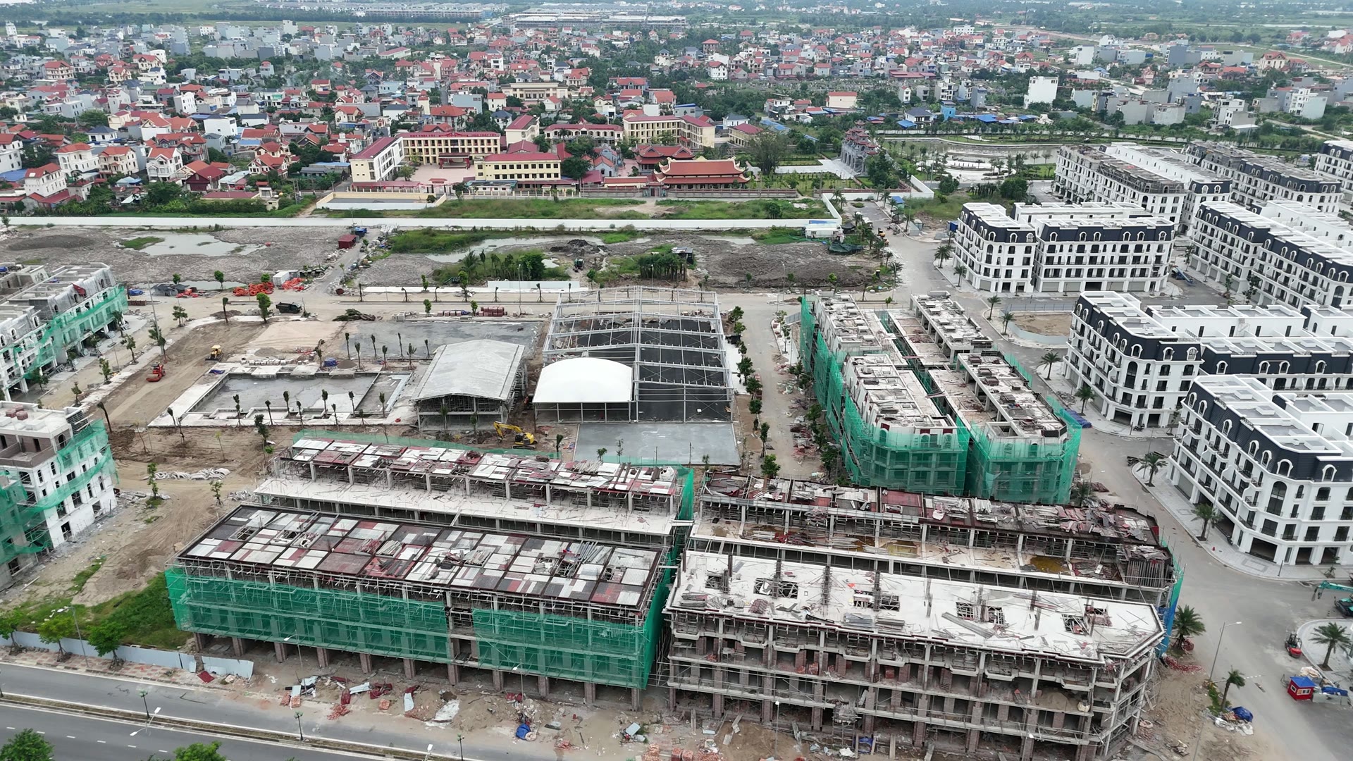 Cụm tiện ích giữa khu Happy Garden ở Hoàng Huy New City gồm bể bơi, khối nhà mái vòm trắng, bộ khung thép sân thể thao chưa lợp mái và hai mảng sân đã làm xong mặt nền, phía trước là các dãy nhà đang hoàn thiện