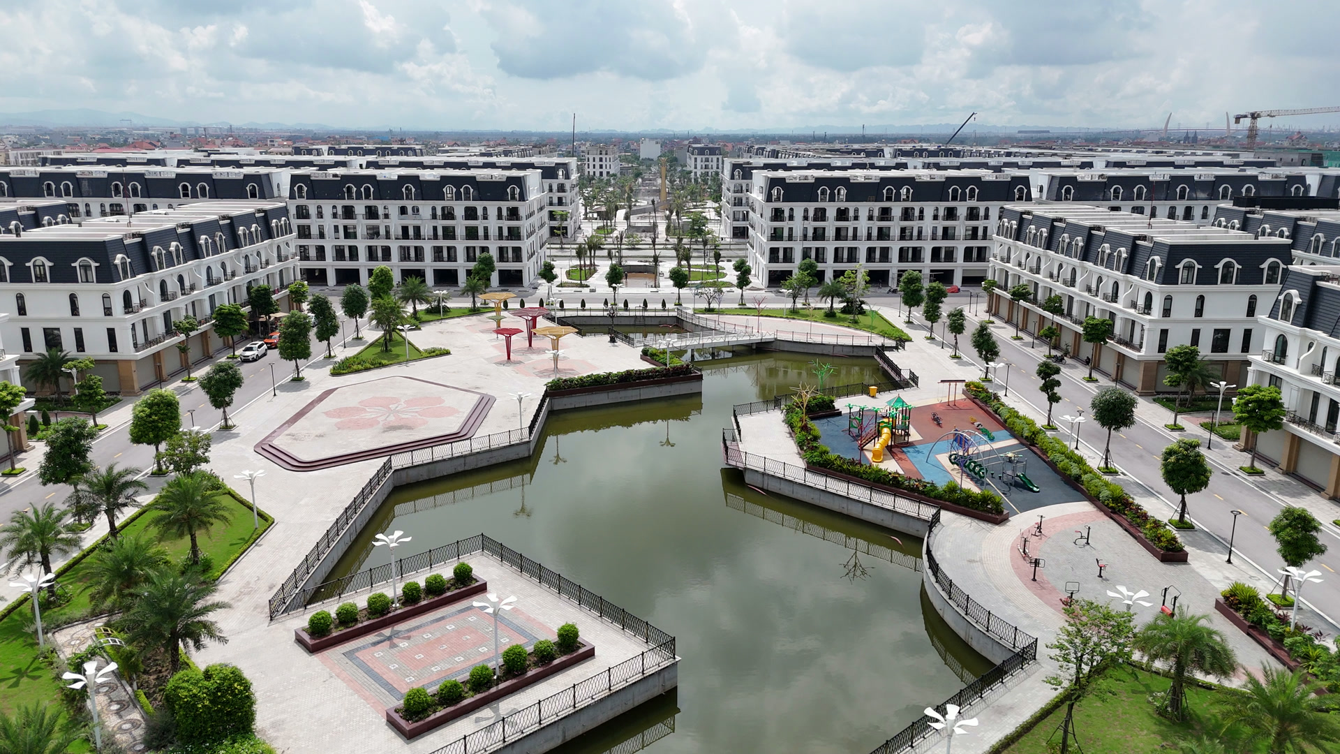 Hồ cảnh quan và sân chơi trẻ em nằm giữa hai dãy nhà thấp tầng đã hoàn thiện ở Hoàng Huy New City, có đường dạo lát gạch và cây xanh