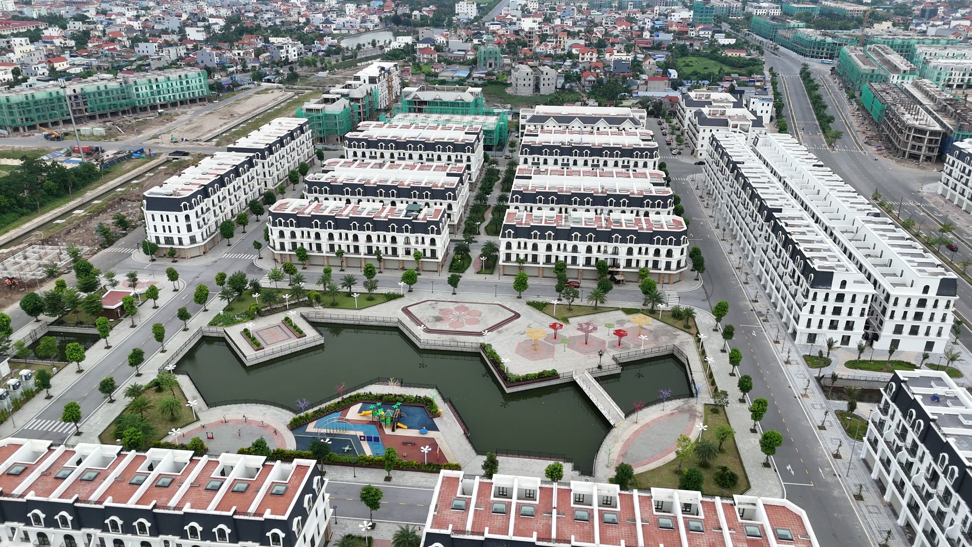 Công viên hồ giữa khu Nữ Hoàng của Hoàng Huy New City với quảng trường lát đá, sân chơi trẻ em và hồ nước, xung quanh là các dãy nhà đã hoàn thiện có người ở
