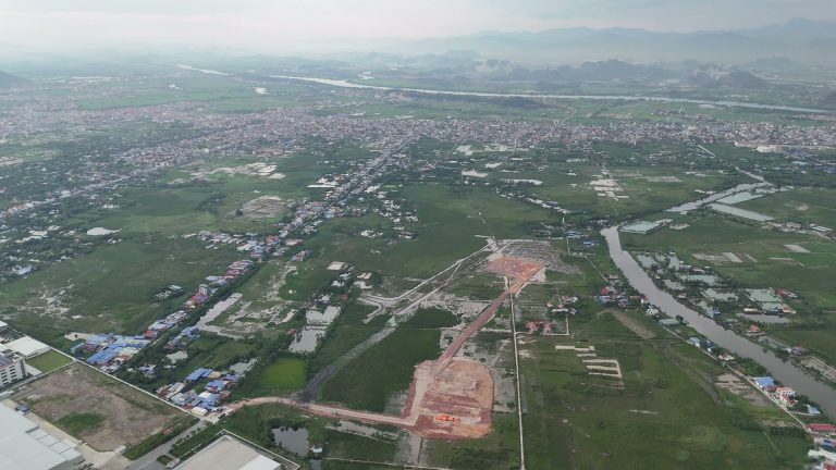 Con đường đất đỏ mới đắp và mảng đất đã san nền giữa ruộng ở khu công nghiệp Thủy Nguyên cuối tháng 8 năm 2026, góc dưới bên trái là mái nhà xưởng khu công nghiệp VSIP