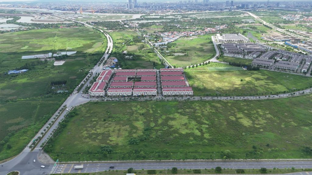 Dãy nhà phố mái đỏ đã xây xong của khu đô thị VSIP nằm giữa những vạt đất còn trống rộng ở Bắc Sông Cấm, phía xa bên kia sông là nội đô Hải Phòng