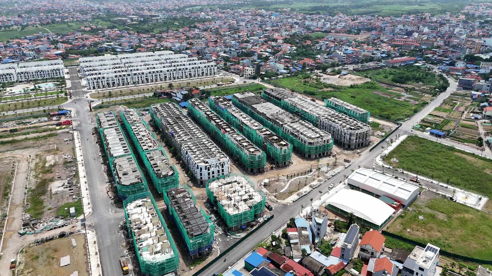 Phân khu Phú Quý của Vlasta Thủy Nguyên, nhiều dãy nhà còn phủ lưới xanh gần kín, một số dãy đã tháo lưới lộ ra tường trắng bên dưới