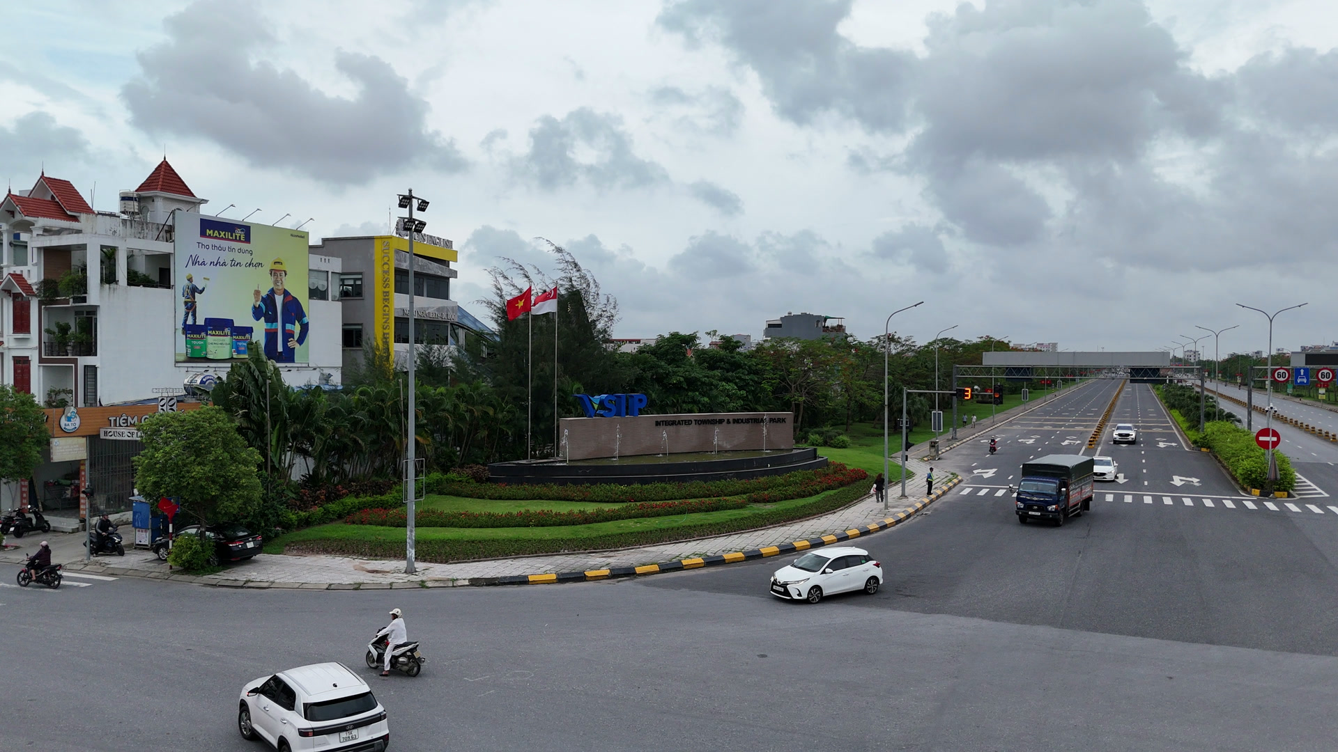 Hàng quán và cửa hàng dịch vụ nằm ngoài cổng khu công nghiệp VSIP Hải Phòng, xe máy và ô tô qua lại trên nút giao