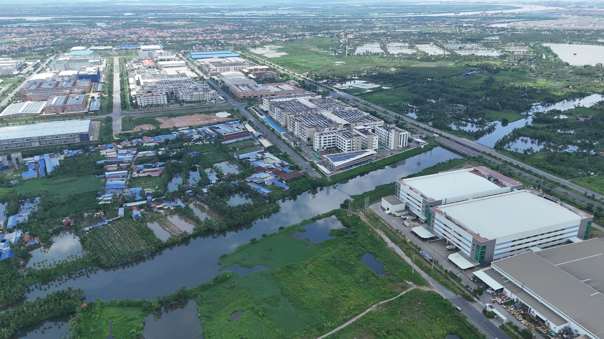 Nhà máy trong khu công nghiệp VSIP Hải Phòng nằm xen giữa những mảng ao đầm và khu dân cư có mái nhà thấp, phía xa là thêm nhiều dãy nhà xưởng