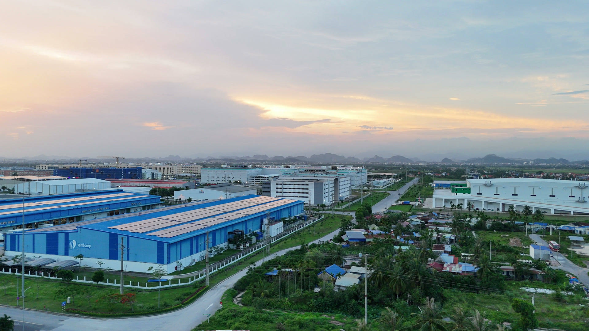 Dãy nhà xưởng mái xanh trong khu công nghiệp VSIP Hải Phòng nằm ngay cạnh khu dân cư và ruộng còn xen kẽ