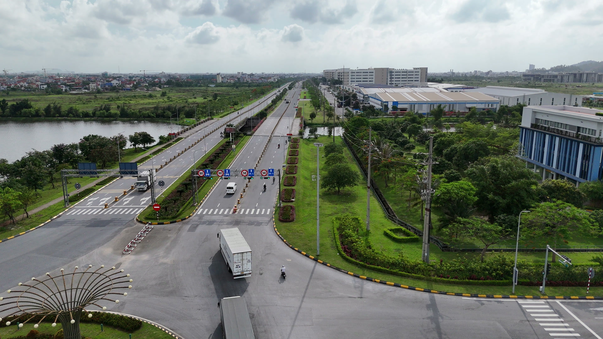 Trục đường chính trong khu công nghiệp VSIP Hải Phòng rộng nhiều làn, có xe container và xe tải đang chạy, hai bên là dải cây xanh và nhà xưởng