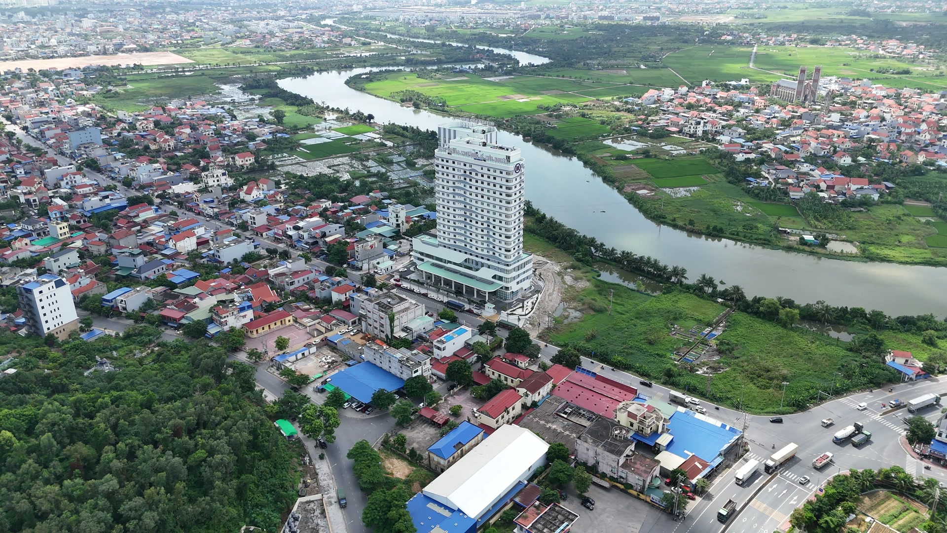 Bệnh viện Đa khoa Quốc tế Thủy Nguyên nhìn từ trên cao, nằm sát mặt đường lớn giữa khu dân cư dày đặc, phía sau là con sông uốn vòng và đồng ruộng