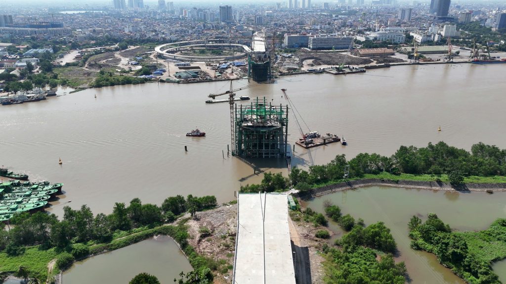 Hai trụ tháp cầu Nguyễn Trãi giữa sông Cấm còn quây giàn giáo, chưa có phần tháp nhô lên, phía xa là vòng xoắn và nội thành Hải Phòng
