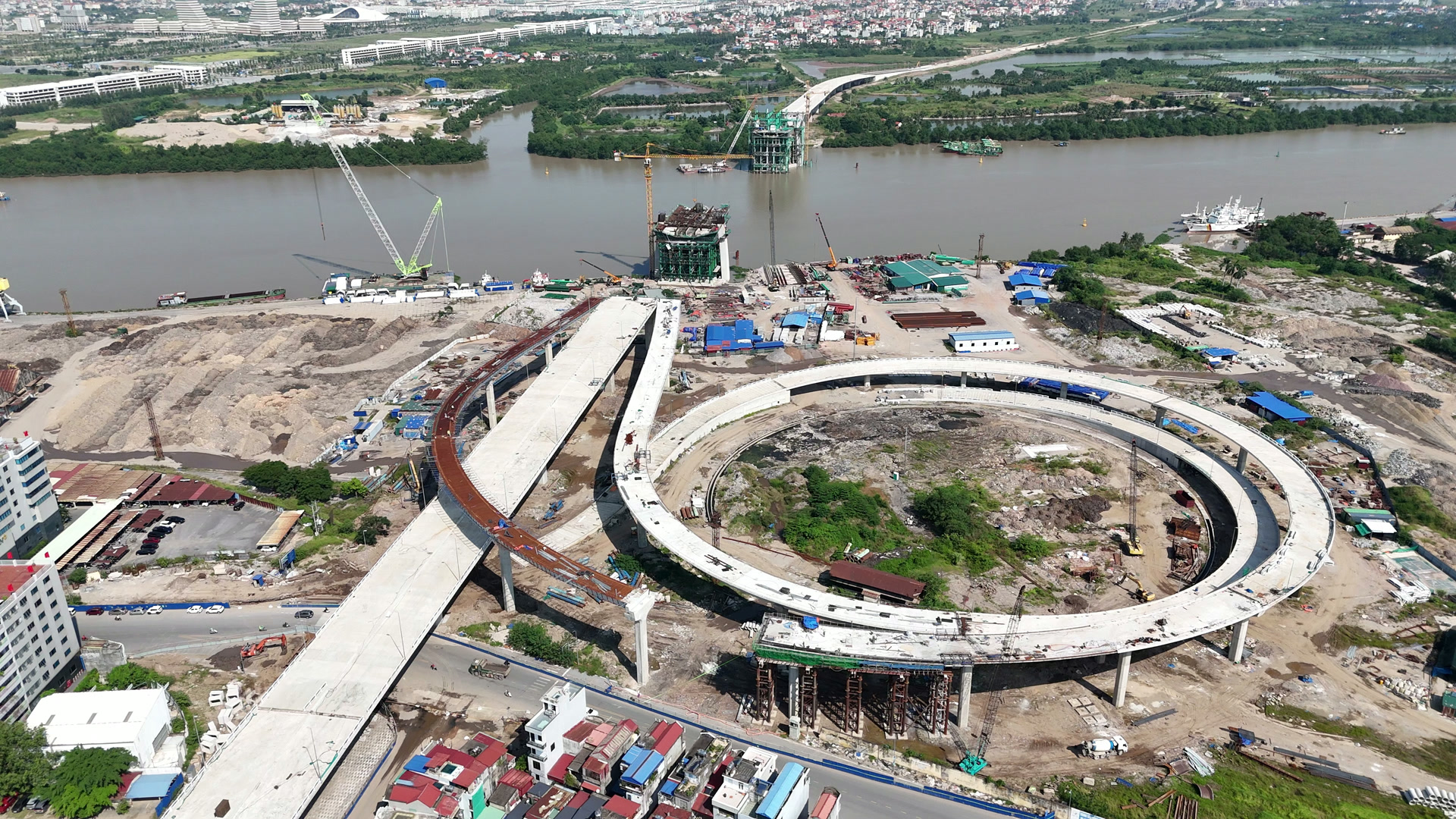 Vòng xoắn cầu Nguyễn Trãi phía nội đô sát bờ sông Cấm, mặt bê tông trắng chạy gần trọn vòng, nhánh cong bên cạnh trục chính vẫn là dầm thép nâu đỏ, xa xa là hai trụ tháp giữa sông