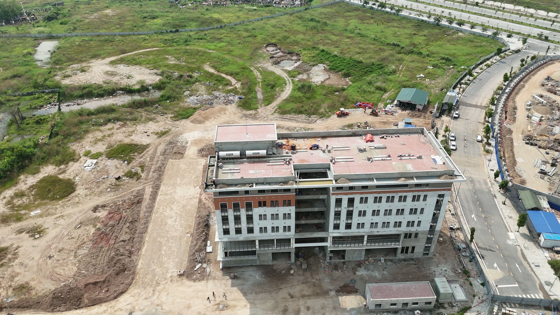Toà nhà đầu tiên của EQuest nhìn từ trên xuống, phần giữa toà còn để trần chưa làm mặt ngoài, sân và lối đi quanh nhà vẫn là đất, phía sau là bãi đất trống chưa xây