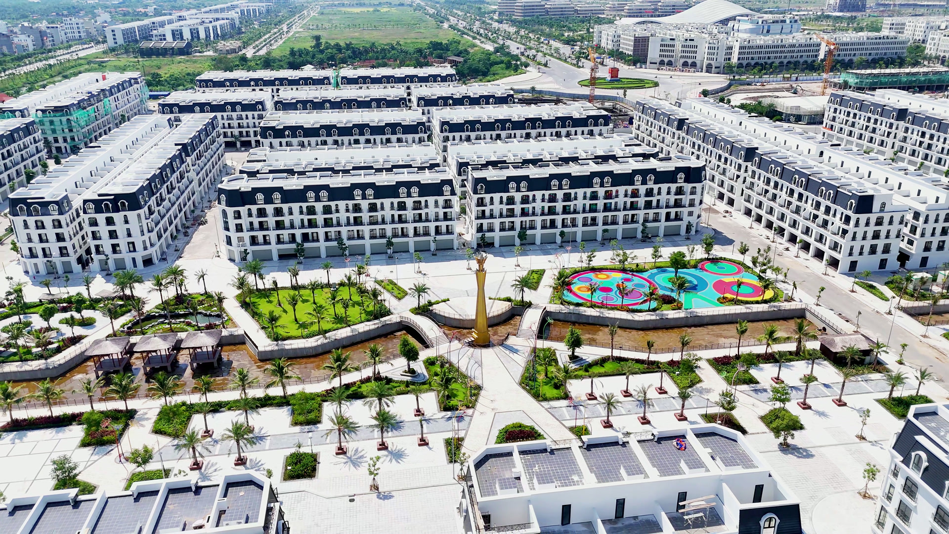 Công viên giữa khu nhà phố ở Hoàng Huy New City, quảng trường lát đá, kênh nước cảnh quan, hàng dừa dọc lối đi và sân chơi trẻ em nhiều màu ở một góc
