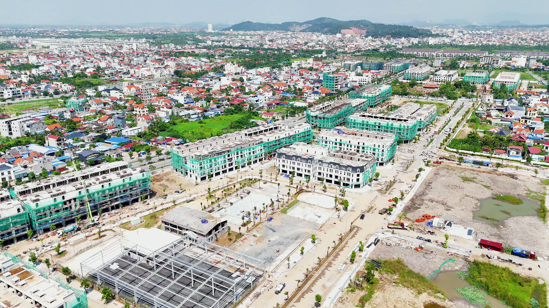 Cụm tiện ích giữa một khu nhà phố đang xây ở Hoàng Huy New City, khung thép công trình và các mặt sân đang làm nền, xung quanh là các dãy nhà còn bọc lưới xanh