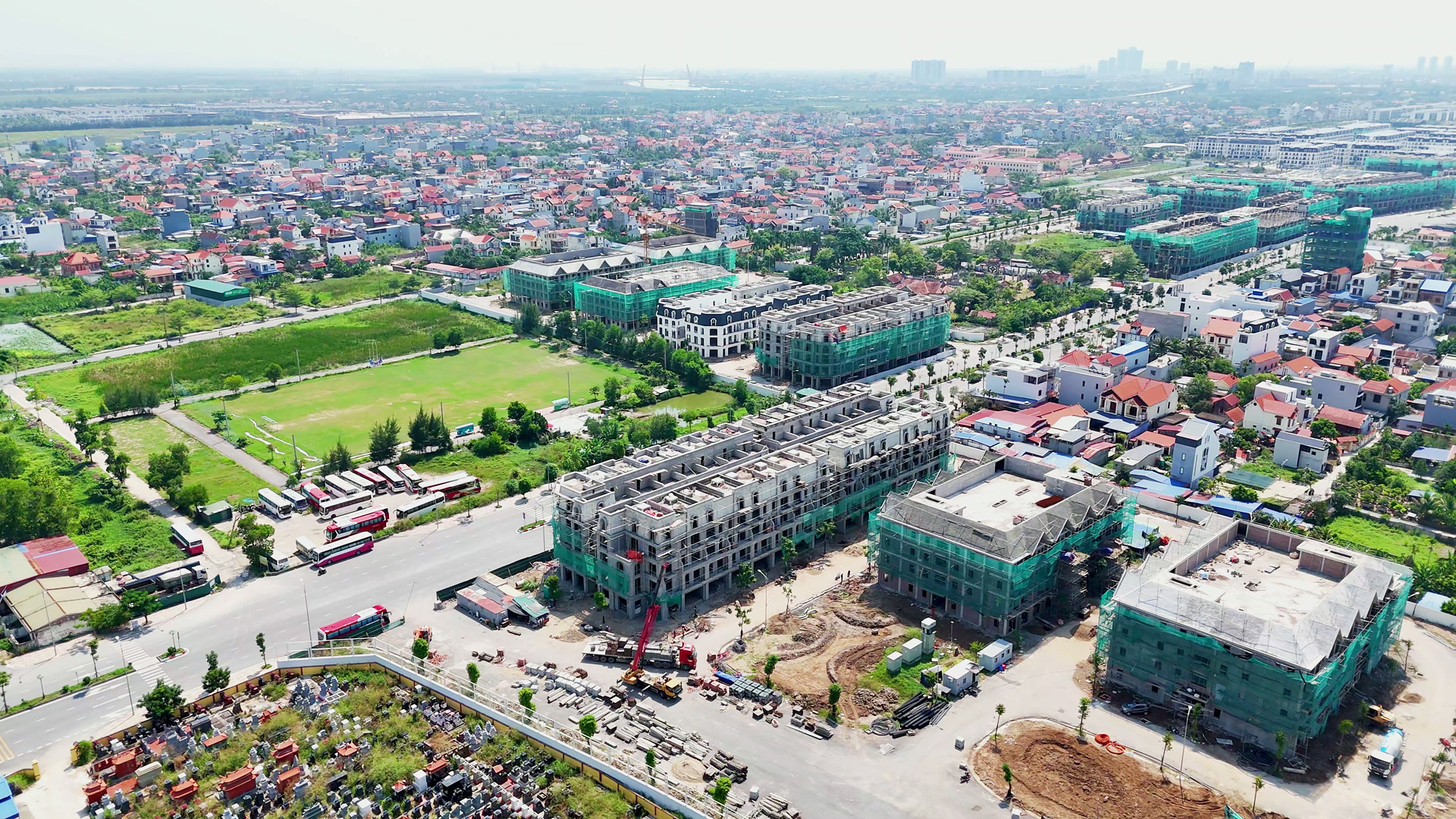 Các dãy nhà phố đã xây lên tới mái nhưng mặt ngoài còn thô ở Hoàng Huy New City, cạnh đường công trường, phía sau là sân bóng và khu dân cư cũ