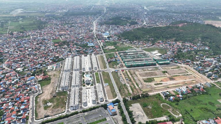 Toàn cảnh khu đô thị Vlasta Thủy Nguyên nhìn từ trên cao, các dãy nhà thấp tầng màu trắng nằm giữa khu dân cư dày đặc, cạnh đó là các lô đất còn trống và đồi cây xanh phía sau
