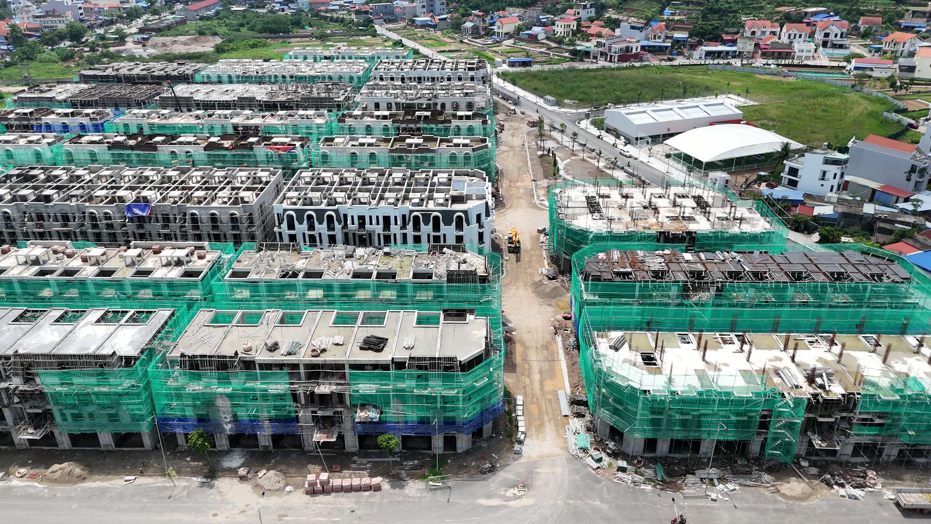 Các dãy nhà phố đang xây ở Vlasta Thủy Nguyên cuối tháng 8/2026, phần lớn còn quây lưới xanh và giàn giáo, mái đã đổ, đường công trường chạy giữa các dãy