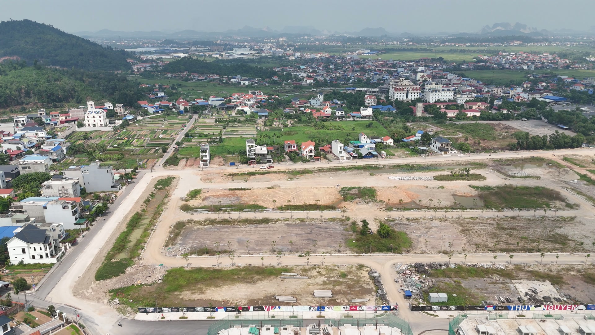 Bãi đất rộng ở Vlasta Thủy Nguyên đã san phẳng và chia thành từng ô, giữa các ô là đường nội bộ có cây hai bên, xung quanh là nhà dân, phía xa là các dãy nhà phố